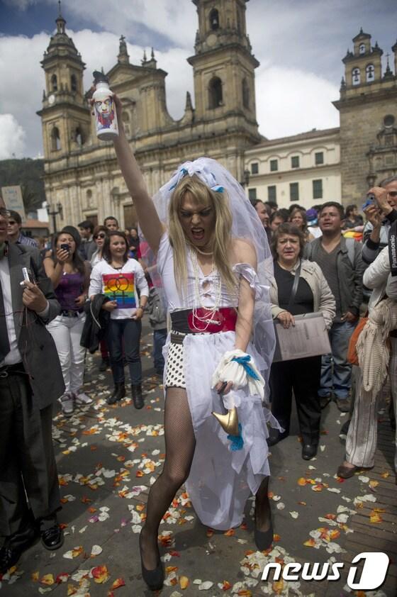 본문 이미지 - 17일(현지시간) 한 LGTB(레즈비언·게이·트렌스젠더·바이섹슈얼) 권리 운동가가 콜롬비아 국회의사당 앞에서 웨딩드레스 형태의 옷을 입고 동성 결혼 합법화 지지 시위를 하고 있다. © AFP=News1 