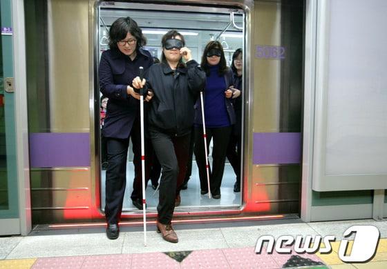 본문 이미지 - 장애인의 날을 하루 앞두고 서울도시철도공사 직원들이 19일 오후 지하철 5호선 마장역에서 왕십리역까지 안대로 눈을 가린 채 지팡이를 사용하여 열차 승·하차 과정을 체험하고 있다. (서울도시철도공사 제공) 2013.4.19/뉴스1