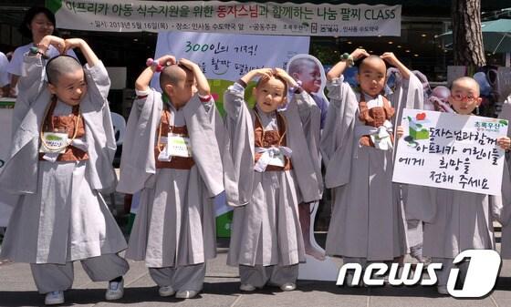 본문 이미지 - 조계사 동자스님들이 16일 오전 서울 종로구 인사동 수도약국 앞에서 열린 '동자스님의 아프리카 친구를 소개합니다(동·아·소)' 캠페인에서 나눔팔찌를 차고 기념 촬영을 하고 있다. 초록우산 어린이재단과 조계사는 5월 한달간 동·아·소 캠페인을 열고 다양한 아프리카 아동 돕기 활동을 펼칠 예정이다. 2013.5.16/뉴스1 © News1   안은나 기자