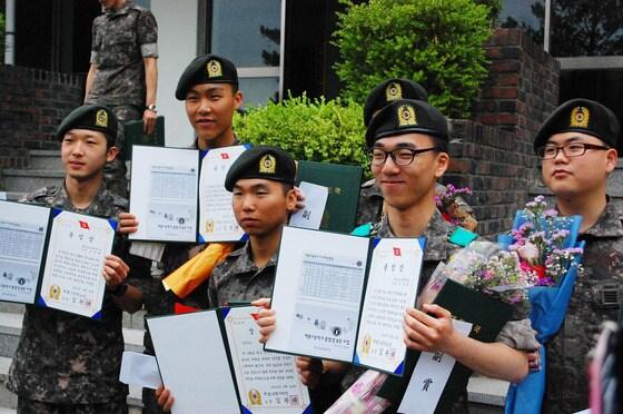 본문 이미지 - 20일 육군 제32보병사단에서 고교 검정고시를 합격한 부대원을 대상으로 제2회 백룡고 졸업식이 열렸다. 졸업생들이 졸업장을 펼쳐보이며 환하게 웃고 있다. © News1  