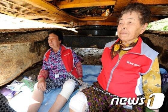 본문 이미지 - 한전이 이틀째 밀양 송전탑 공사를 재개한 21일 오후 밀양 단장면 바드리마을 송전탑 공사 현장에서 마을 주민들이 굴삭기에 쇠사슬과 끈으로 몸을 묶어 시위를 벌이고 있다. 2013.5.21/뉴스1 © News1 전혜원 기자