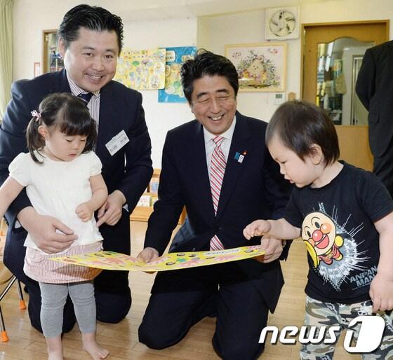 본문 이미지 -  아베 신조 일본 총리(가운데)가 21일 일본 요코하마 소재의 유치원에서 아이들과 함께 놀고 있다. 요코하마시는 여성의  출산 후 복직 불가능 문제를 해결하기 위해 유치원과 보육원의 입학을 기다리는 대기인원을 줄이는 정책을 시행하고 있다.  © AFP=News1  