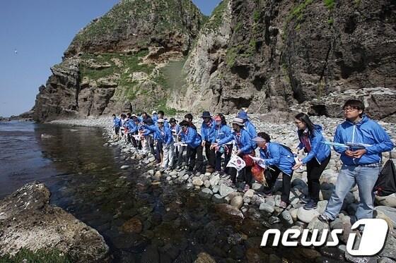 본문 이미지 - 23일 독도를 방문한 대구은행 사이버독도지점 탐방단이 고유종인 어린 왕전복을 방류하고 있다./사진제공=대구은행© News1 