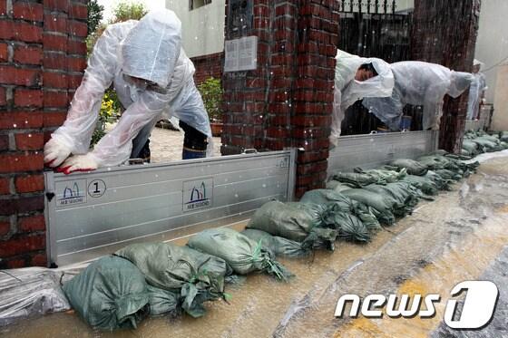 본문 이미지 - 장마철 집중호우를 대비해 13일 오전 서울 서초구 양재동 주택가에서 열린 지하주택 침수 예방을 위한 차수판 설치 훈련에서 참가자들이 차수판과 모래주머니를 설치하고 있다.2013.6.13/뉴스1 © News1 이광호 기자