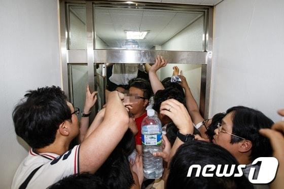 본문 이미지 - 한국일보에 용역을 동원한 편집국 봉쇄와 기사 집배신시스템 폐쇄라는 한국 언론사상 초유의 사태가 발생한 가운데 17일 서울 중구 남대문로 2가 본사 편집국이 연결된 비상계단 철문이 개방되며 편집국으로 들어가려던 기자들이 용역들에게 막혀 복도 유리문을 사이에 두고 대치하고 있다. 2013.6.17/뉴스1 © News1 유승관 기자