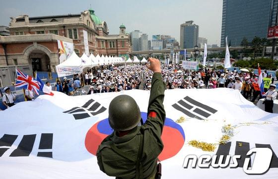 본문 이미지 - 한국자유총연맹 회원들이 서울역 광장에서 열린 나라사랑 공감한마당 행사에서 대형태극기를 펼치고 만세삼창을 하고 있다. © News1 박정호 기자
