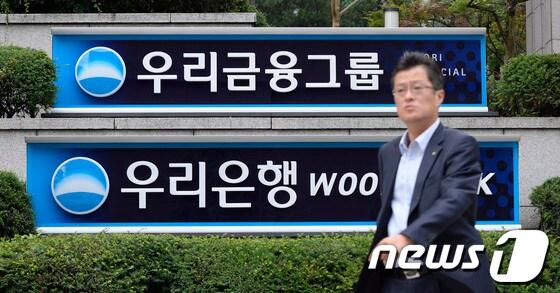 본문 이미지 - 정부가 우리금융지주의 민영화 방안을 발표한 지난 달 26일 서울 중구 우리금융그룹 본사 앞으로 한 시민이 지나가고 있다. 우리금융지주의 14개 자회사는 3개 그룹으로 나뉘어 각각 예보 또는 우리금융지주가 매각을 추진하며, 매각이 용이하도록 분할, 합병 등의 절차와 매각절차를 동시 추진하게 된다. 2013.6.26/뉴스1 © News1   박지혜 기자
