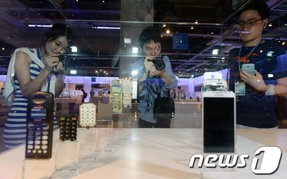 본문 이미지 - 경기도 수원시 영통구 삼성전자 디지털시티 R5 연구소에서 열린 삼성전자 이노베이션 포럼 전시장에서 관람객들이 삼성전자의 1995년 애니콜 모델과 2003년 겔럭시S4 모델을 비교 관람하고 있다.2013.6.27 ⓒ 뉴스1