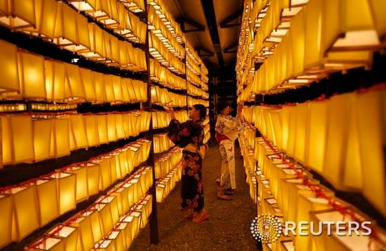 본문 이미지 - p13일 도쿄 야스쿠니 신사에서 열린 미타나(영혼) 축제 도중 유카타를 입은 여성들이 종이등을 바라보고 있다. 240여만명의 전몰자가 안치되어 있는 야스쿠니 신사에서는 축제기간 나흘동안 3만여개의 등이 불을 밝히고 있다. © 로이터=뉴스1 /p