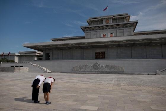 본문 이미지 - 두 학생이 평양 금수산태양궁전에 걸려있는 김일성(왼쪽) 주석과 김정일(오른쪽) 국방위원장 사진에 인사하고 있다. 금수산태양궁전은 이 둘의 시신이 안치돼 있는 곳이다.  © AFP=뉴스1   이재영 인턴기자