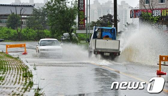본문 이미지 - 갑자기 내린 폭우로 하수도가 역류해 차량 통행에 지장을 주고 있다. /뉴스1 © News1 
