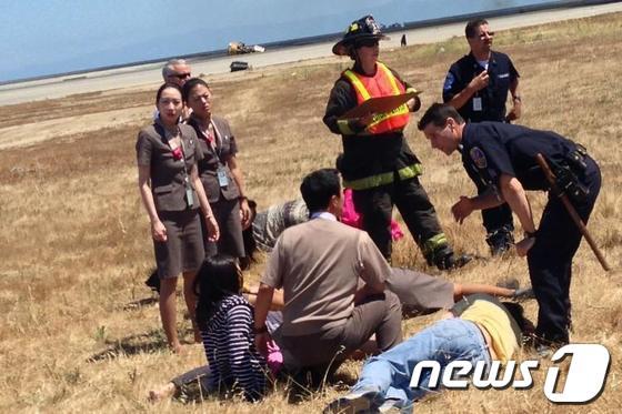 본문 이미지 - 피해자들을 돕는 이윤혜 아시아나항공 OZ214편 최선임 승무원&#40;좌&#41;&#40;사진=월스트리트저널 페이스북&#41; © News1 