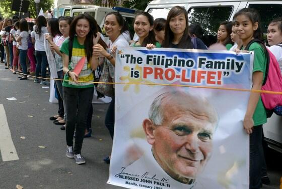 본문 이미지 - 요한 바오로 2세 전 교황 사진을 든 필리핀 가톨릭 신자들이 9일(현지시간) 대법원 앞에서 정부가 피임법과 성 교육을 지원토록 규정한 법률에 반대하고 있다. 필리핀은 전체 인구의 80%가 가톨릭 신자로 가톨릭 교계는 최근 통과된 이 법안에 대해 강력히 반대하고 있다. 현재 대법원에서 법안을 심사하고 있다. © AFP=뉴스1  