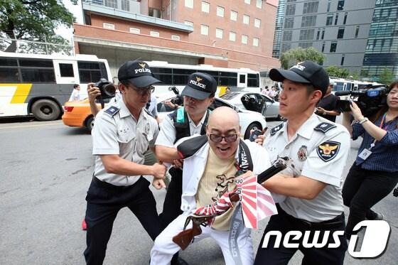 본문 이미지 - 광복절을 하루 앞둔 14일 오전 서울 종로구 중학동 주한일본대사관 앞에서 오천도 애국국민운동대연합 대표가 일본 군국주의를 상징하는 욱일승천기가 둘러진 엽총과 계란을 들고 대사관 진입을 시도하다 경찰의 제지를 받고 있다. © News1 한재호 기자