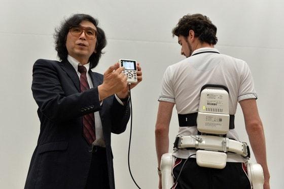 본문 이미지 - 일본 로봇 기업 사이버다인(Cyberdyne) 의 회장 산카이 요시유키 쓰쿠바 대학 교수(왼쪽)가 5일 쓰쿠바 본사에서 새로 개발한 의학용 신체보조 로봇 슈트인 HAL을 선보이고 있다. 사람의 동선을 파악하여 움직이는 것을 도와주는 HAL은 장애인과 노인 등의 재활치료에 도움되며 유럽 인증국에서는 의학용 장치로 이미 허가를 받은 상태다. © AFP=뉴스1  