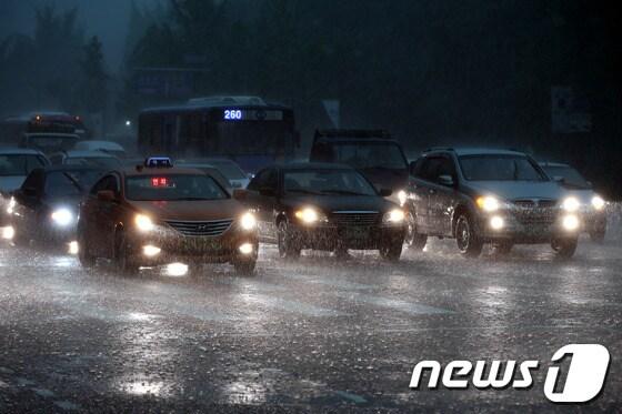 본문 이미지 - 천둥, 번개를 동반한 비와 함께 한낮에도 어둠이 내린 6일 오후 서울 여의도에서 차량들이 전조등을 켜고 운행하고 있다.2013.8.6/뉴스1 © News1   이광호 기자