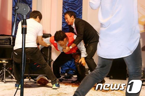 본문 이미지 - 7일 오후 서울 청계천 광통교에서 열린 김조광수 감독과 김승환 대표의 결혼식에 한 남성이 난입해 된장을 뿌린 뒤 끌려 나가고 있다. © News1 