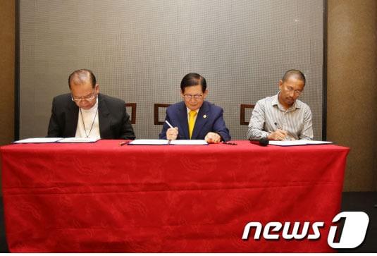 본문 이미지 - 지난달 25일 필리핀 제너럴 산토스市의 한 호텔에서 이만희 ‘하늘문화세계평화광복 평화사절단’ 대표(가운데)와 페르난도 카펠라 민다나오 다바오 前 대주교, 이스마엘 망구다다투 민다나오 이슬람 자치구 마귄다나오 주지사가 전쟁종식·세계평화 협약서에 서명하고 있다./ 사진제공=하늘문화세계평화광복 평화사절단© News1  