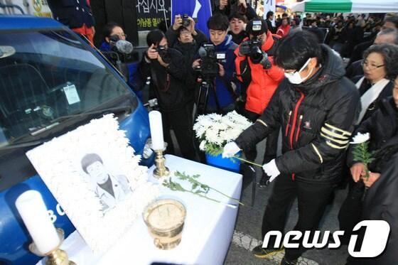 본문 이미지 - '박근혜 사퇴, 특검 실시'를 외치며 서울역 앞 고가도로에서 분신해 숨진 고 이남종(40)씨의 영결식이 4일 오후 광주 금남로에서 진행됐다. 이씨의 동생이 헌화하고 있다. 2014.1.4/뉴스1 © News1   김태성 기자