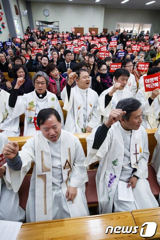 본문 이미지 - 6일 오후 경기 화성시 기산성당에서 열린 천주교정의구현사제단 수원교구 주최 관권 부정선거 진상규명 및 박근혜 정권의 회개와 퇴진을 촉구하는 시국미사에서 참석자들이 '이명박 구속' '박근혜 퇴진' '민주주의 지켜내자라' 쓰여진 손팻말을 들고 구호를 외치고 있다. 2014. 1. 6/뉴스1 유승관 기자 © News1 