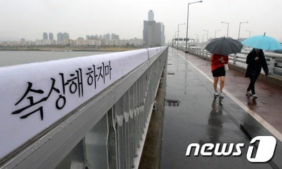 본문 이미지 - 21일 오후 서울 마포대교에 적힌 자살예방 문구 옆으로 시민들이 지나가고 있다. 최근 4년간 전국 교량(다리)에서의 자살이 2.3배로 증가한 것으로 나타났다. 특히 마포대교에서 가장 자살 시도가 많은 것으로 조사됐다. 2014.10.21/뉴스1 ⓒ News1 손형주 기자