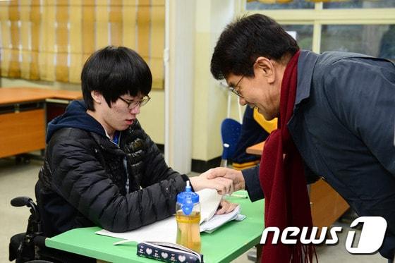 본문 이미지 - 13일 오전 중증 장애인을 위한 수험장인 구월중학교를 방문한 이청연 인천교육감이 수험생과 악수를 나누고 있다. 사진 제공=인천시교육청.ⓒ News1