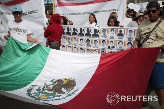 본문 이미지 - 대학생들의 실종에 이괄라 시 시장 부부가 개입되있다는 것이 알려지면서 지난달 22일 분노한 시민들이 멕시코 국기를 펼치고 시위하고 있다. ⓒ 로이터=뉴스1