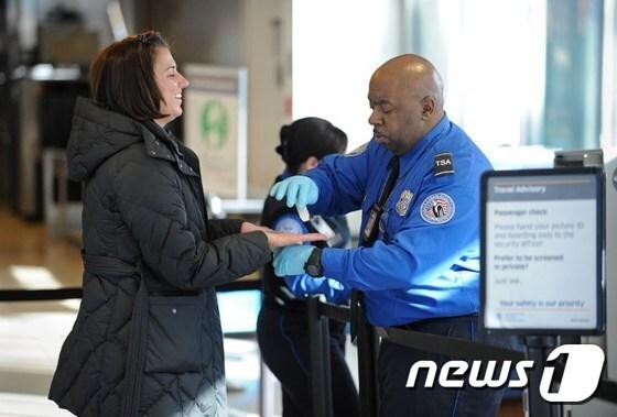 본문 이미지 - 뉴욕 라과디아 공항의 한 미국 교통안전국(TSA) 직원이 승객을 검사하고 있다.ⓒ AFP=뉴스1