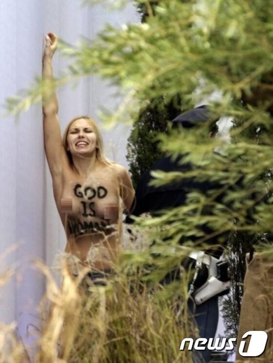 본문 이미지 - 성탄절인 25일 바티칸 베드로광장서 토플리스 시위하는 페멘 여성운동가. 그의 가슴에는 '신은 여성이다'라는 문귀가 쓰여있다. ⓒ AFP=News1