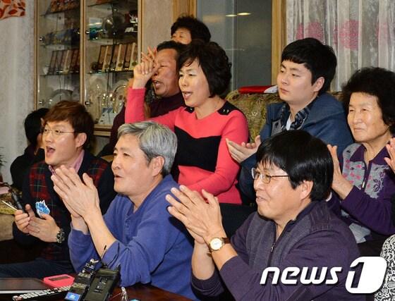 본문 이미지 - '빙속여제' 이상화 선수의 부모 이우근(앞줄 가운데), 김인순(뒷줄 세번째)씨가 14일 새벽 서울 동대문구 자택에서 2014 소치 동계올림픽 스피드스케이팅 여자 1000m에 출전한 이 선수의 중계방송을 지켜보고 있다.이 선수는 이날 경기에서 1분 15초 94의 기록으로 전체 36명 선수 중 12위를 기록했다. 2014.2.14/뉴스1 © News1   박철중 기자