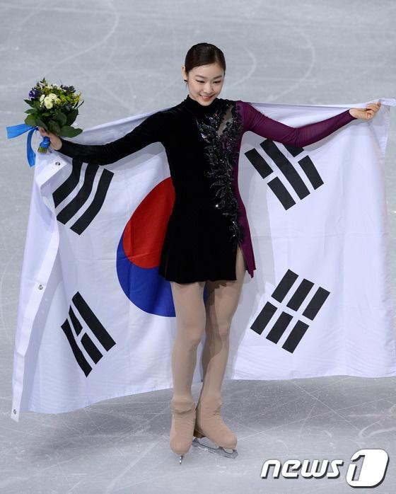 본문 이미지 - '피겨 여왕' 김연아가 21일(한국시간) 러시아 소치 해안 클러스터 아이스버그 스케이팅 팔라스 경기장에서 열린 프리 스케이팅 경기 후 꽃다발과 태극기를 들고 취재진을 향해 포즈를 취하고 있다.  2014.2.21/뉴스1 DB