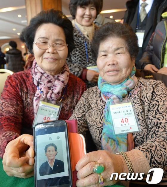 본문 이미지 - 2차 남북 이산가족 상봉행사를 하루 앞둔 22일 강원도 속초 한화콘도에서 남측 상봉 대상자 김사문, 김영순 할머니가 북측 언니 사진을 꺼내 보이며 활짝 웃고 있다. 2014.2.22/뉴스1 © News1   사진공동취재단