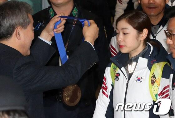 본문 이미지 - 2014 소치 동계올림픽 대표팀 김연아 선수가 25일 오후 인천국제공항 입국장을 통해 귀국해 유진룡 문화체육관광부 장관에게 초콜렛으로 만든 &#39;국민행복 메달&#39;을 수여받고 있다. 2014.2.25/뉴스1 © News1   한재호 기자