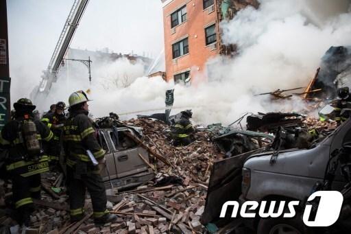 본문 이미지 - 12일(현지시간) 뉴욕 맨해튼 이스트 할렘 1644 파크 애버뉴 아파트 건물 폭발과 붕괴로 인한 잔해들 사이에서 연기가 자욱하게 일어나고 있는 가운데 소방관들이 출동해 있다. © AFP=뉴스1  