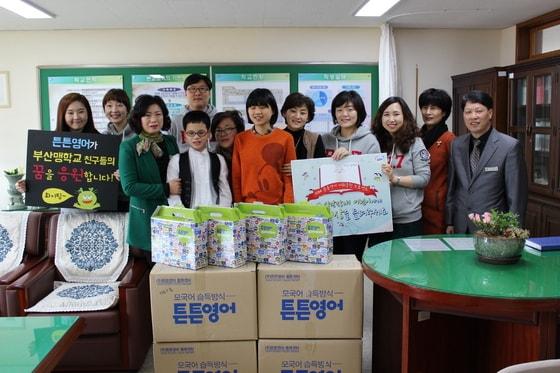 본문 이미지 - 튼튼영어 임직원들이  부산맹학교 어린이들에게 점자로 된 영어 교재를  전달하고 있다. /  © News1  