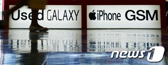 본문 이미지 - 서울 용산의 한 전자매장에 부착된 삼성전자와 애플의 광고판 앞으로 시민들이 지나고 있다. 2014.3.31/뉴스1 © News1   양동욱 기자