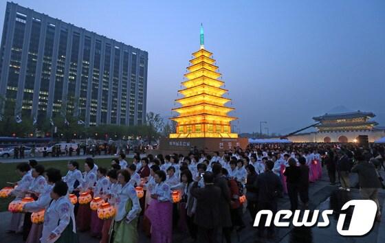 본문 이미지 - 부처님오신날을 앞두고 지난 16일 오후 서울 광화문 광장에서 열린 '미륵사지 탑등' 점등식에서 불자들이 연등을 들고 탑 주위를 돌고 있다. /뉴스1 © News1 송은석 기자