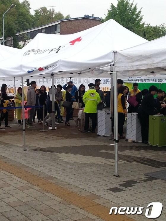 본문 이미지 -                                         사랑의 열매 봉사단원들이 안산 올림픽체육관 합동분향소를 찾은 조문객들의 안내를 하고 있다. © News1  