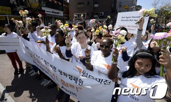 본문 이미지 - 르완다 대학살 생존자와 르완다인들, 한국 대학생들이 6일 오전 서울 마포구 홍대 걷고싶은 거리에서 열린 르완다 대학살 20주기 추도식 '꽃으로도 때리지 말라'에서 평화와 화해를 상징하는 꽃을 들고 있다.2014.4.6/뉴스1 © News1   안은나 기자