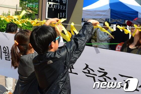 본문 이미지 - 1일 세월호 참사 희생자들을 추모하기 위해 속초시내 S호텔 앞에 마련된 속초고성양양 합동 분향소에 어린이 2명이 정성스레 노란리본을 메달고 있다. 2014.5.1/뉴스1 © News1   엄용주 