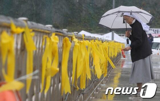 본문 이미지 - 세월호 침몰사고 29일째인 14일 오후 전남 진도군 팽목항 등댓길에서 한 수녀가 노란 리본에 적힌 글을 읽고 있다. 2014.5.14/뉴스1 © News1   박지혜 기자