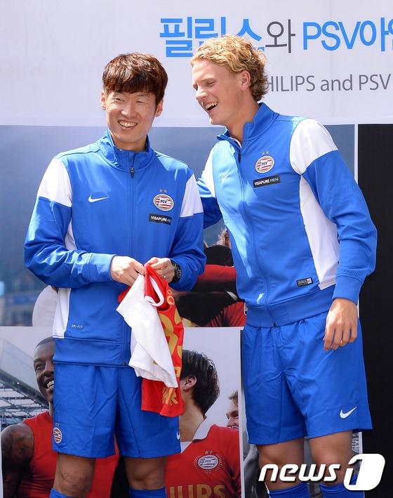 본문 이미지 - 21일 오후 서울 한남동 그랜드 하얏트 호텔에서 열린 'PSV 아인트호벤 필립스와 창단 100주년' 기념행사 및 팬미팅에 참석한 박지성이 동료 오스카 힐리에 마르크로 부터 유아용 PSV 아인트호벤 구단 유니폼을 전달 받고 있다.2014.5.21/뉴스1 © News1   이동원 기자