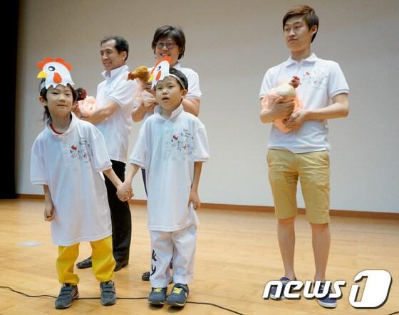 본문 이미지 - 닭갈비 도시 춘천을 닭의 명품도시로 만들기 위한 다그로월드 협동조합이 27일 강원대학교 60주년기념관 국제회의실에서 '창립 및 닭도시 선포식'을 개최했다. 이날 닭모자를 쓴 아이들과 닭이 함께 서있고 닭 울음소리가 스피커를 통해 흘러나오고 있다.2014.5.27/뉴스1 © News1   황준 기자