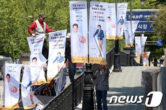 본문 이미지 - 6·4 전국동시지방선거를 30일 앞둔 5일 오전 서울 종로구 연건동 도로변에서 서울시선거관리위원회 관계자들이 사전투표와 투표참여를 독려하는 현수기&#40;깃발&#41;를 가로등에 설치하고 있다. 2014.5.5/뉴스1 © News1 한재호 기자