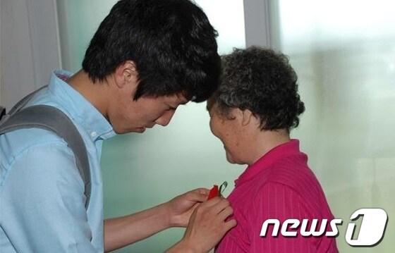 본문 이미지 - 나라사랑앞섬이 목원대 학생이 보훈가족에게 직접 만든 카네이션을 달아주고 있다. © News1 