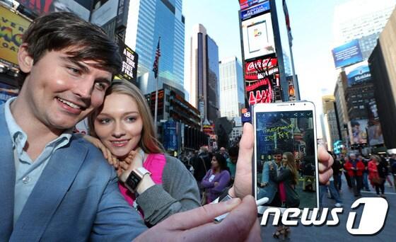 본문 이미지 - 지난 4월 말 미국 뉴욕 맨해튼 타임스 스퀘어에서 한 쌍의 연인이 삼성전자 갤럭시노트 3로 촬영한 사진에 S펜으로 글을 남기고 있다. 2014.6.12/뉴스1 © News1   (뉴욕(미국)=뉴스1) 허경 기자