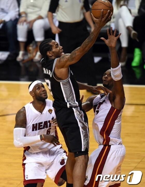 본문 이미지 - 13일(한국시간) 벌어진 2013-14 NBA 파이널 4차전 샌안토니오 스퍼스와 마이애미 히트의 경기에서 카와이 레너드(검은색 유니폼)가 상대 수비수 두 명 사이에서 레이업슛을 시도하고 있다. © AFP=News1  