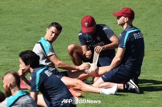 본문 이미지 - 포르투갈 축구대표팀의 공격수 크리스티아누 호날두가 팀 훈련 중 팀 닥터들로부터 무릎에 얼음찜질을 받고 있다. © AFPBBNews=News1  