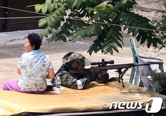 본문 이미지 - 23일 강원도 고성군 현내면 마차진리 마을에서 육군 저격수가 인근 야산에서 군병력과 대치 중인 무장 탈영병 임모 병장을 조준하고 있다.강원도 고성 22사단 GOP에서 총기를 난사한 후 무장탈영한 임모 병장(23)은 이날 오후 2시55분께 군 병력과 대치하던 중 자살을 시도했다. 2014.6.23/뉴스1 © News1   한재호 기자