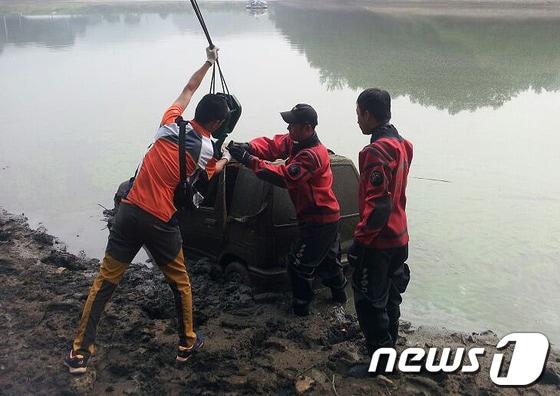 본문 이미지 - 26일 오전 5시 55분께 춘천시 신북읍 용산저수지에서 발견된 티코 승용차를 119 구조대원 등이 인양하고 있다. 해당 차량 안에는 2003년 11월 자신의 남편을 둔기로 때려 숨지게 한 혐의로 지명수배된 여성으로 추정되는 시신이 발견됐다.(춘천소방서 제공) 2014.6.26/뉴스1 © News1   이예지 기자